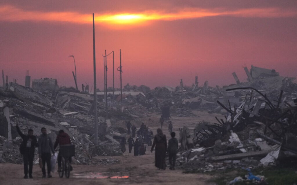 Palestinians walk through the ruins of destroyed buildings as the sun sets over Gaza City, January 4, 2026. (AP Photo/Jehad Alshrafi)