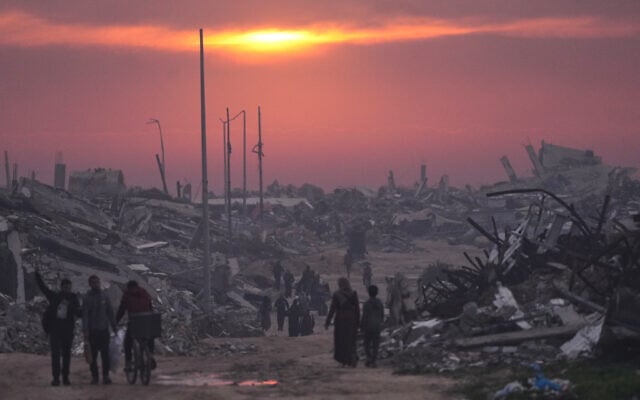 Palestinians walk through the ruins of destroyed buildings as the sun sets over Gaza City, January 4, 2026. (AP Photo/Jehad Alshrafi)