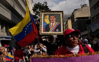 A government supporter holds an image of Venezuelan President Nicolas Maduro during a women's march to demand his return in Caracas, Venezuela, January 6, 2026. (AP/Matias Delacroix)