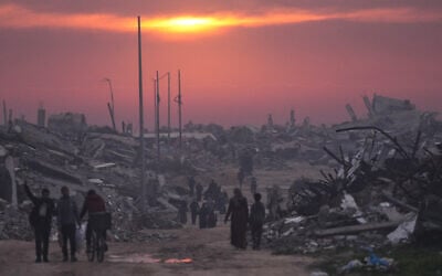 Palestinians walk through the ruins of destroyed buildings as the sun sets over Gaza City, January 4, 2026. (AP Photo/Jehad Alshrafi, File) Palestinians walk through the ruins of destroyed buildings as the sun sets over Gaza City, January 4, 2026. (AP Photo/Jehad Alshrafi, File)