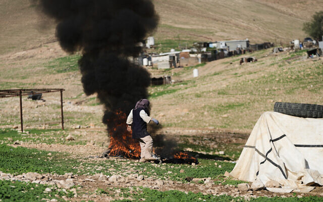 A Palestinian resident of Ras Ein al-Auja village, West Bank burns trash, January 11, 2026. (AP Photo/Mahmoud Illean)