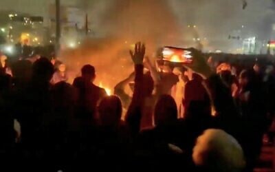 This frame grab from footage circulating on social media shows protesters dancing and cheering around a bonfire in the street in Tehran, Iran, January 9, 2026. (UGC via AP)