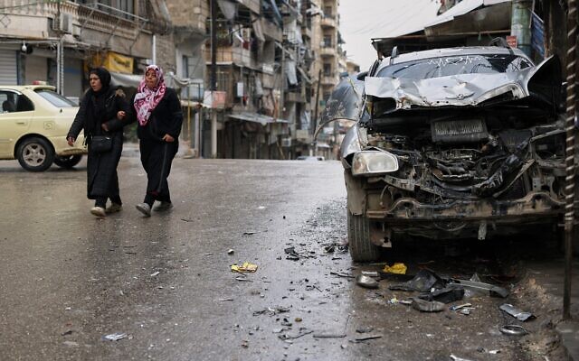 Women walk by a damaged car in the predominantly Kurdish Sheikh Maqsoud neighborhood after days of fighting between government forces and Kurdish fighters in the northern city of Aleppo, Syria, January 13, 2026. (AP Photo/Ghaith Alsayed) Women walk by a damaged car in the predominantly Kurdish Sheikh Maqsoud neighborhood after days of fighting between government forces and Kurdish fighters in the northern city of Aleppo, Syria, January 13, 2026. (AP Photo/Ghaith Alsayed)