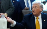 US President Donald Trump gestures to a container of milk before he signs a bill that returns whole milk to school cafeterias across the country, in the Oval Office of the White House, Wednesday, Jan. 14, 2026, in Washington. (AP Photo/Alex Brandon)