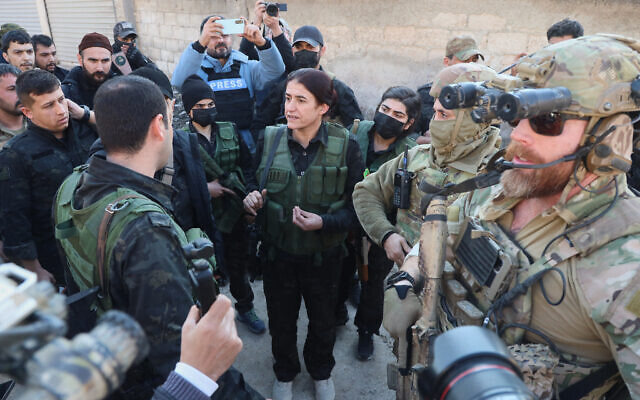 Rohlat Efrin, center, a commander in the US-backed Syrian Democratic Forces, speaks with an SDF member as American soldiers stand guard during a meeting in Deir Hafer, Syria, January 16, 2026. (AP Photo/Baderkhan Ahmad)