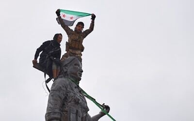 Syrian government soldiers wave a Syrian flag after climbing atop a statue of a female Kurdish fighter, following the takeover of the town from US-backed Syrian Democratic Forces (SDF) during an ongoing push against Kurdish-led forces, in Tabqa, eastern Syria, January 18, 2026. (AP Photo/ Omar Albam) Syrian government soldiers wave a Syrian flag after climbing atop a statue of a female Kurdish fighter, following the takeover of the town from US-backed Syrian Democratic Forces (SDF) during an ongoing push against Kurdish-led forces, in Tabqa, eastern Syria, January 18, 2026. (AP Photo/ Omar Albam)