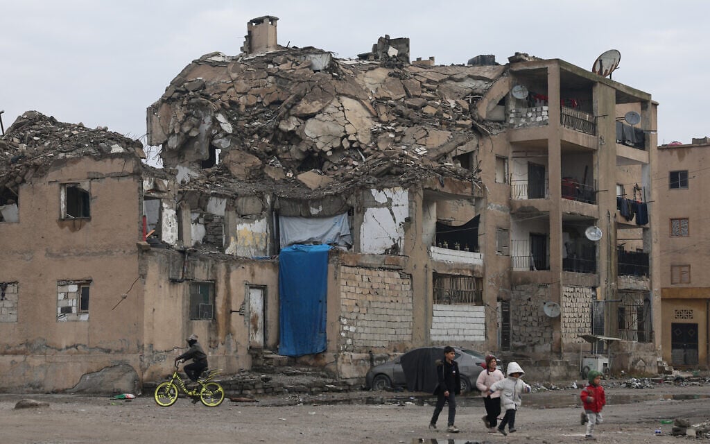 Children walk past a damaged residential building in Raqqa, Syria, January 24, 2026. (AP Photo/Ghaith Alsayed)