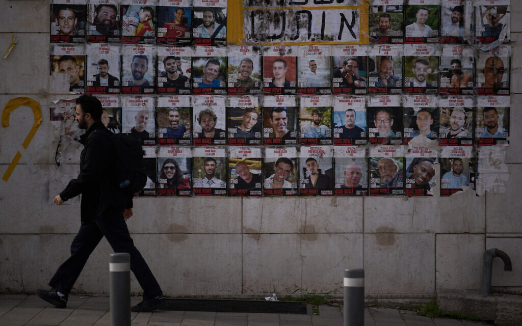 A man walks past photographs of hostages who were kidnapped and held by Hamas, displayed on a street in Jerusalem, Tuesday, Jan. 27, 2026, following the announcement that the remains of the last hostage in Gaza, Ran Gvili, were recovered from the Gaza Strip.  (AP Photo/Leo Correa)