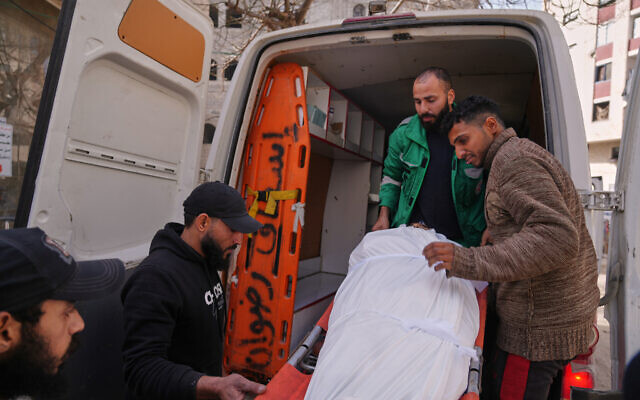 Mohammed Al Rifi, right, looks at the body of his brother Yusuf Al Rifi, who was reportedly killed by Israeli fire, according to health officials, being carried into a vehicle before his funeral at Shifa Hospital, in Gaza City, Tuesday, Jan. 27, 2026. (AP Photo/Jehad Alshrafi)