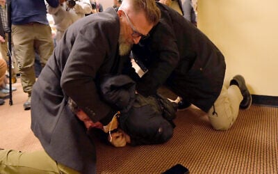 A man is tackled to the ground after spraying an unknown substance on US Rep. Ilhan Omar during a town hall on January 27, 2026, in Minneapolis. (Richard Tsong-Taatarii/Star Tribune via AP)