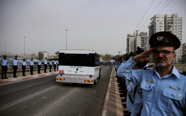 Police officers salute as a convoy carrying the coffin of Ran Gvili, the last hostage whose remains were recovered from the Gaza Strip, passes through Matzliah in central Israel on the way to his funeral, January 28, 2026. (AP Photo/Ohad Zwigenberg)