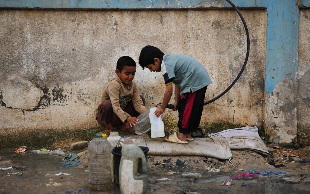 Palestinian children fill plastic bottles with water at a tent camp in Deir al-Balah, Gaza Strip, Jan. 29, 2026. (AP Photo/Abdel Kareem Hana)