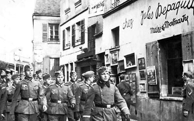 A squad of German soldiers marches through a street in Paris, France, October 24, 1940, while others walk along looking at the shops. (AP Photo)