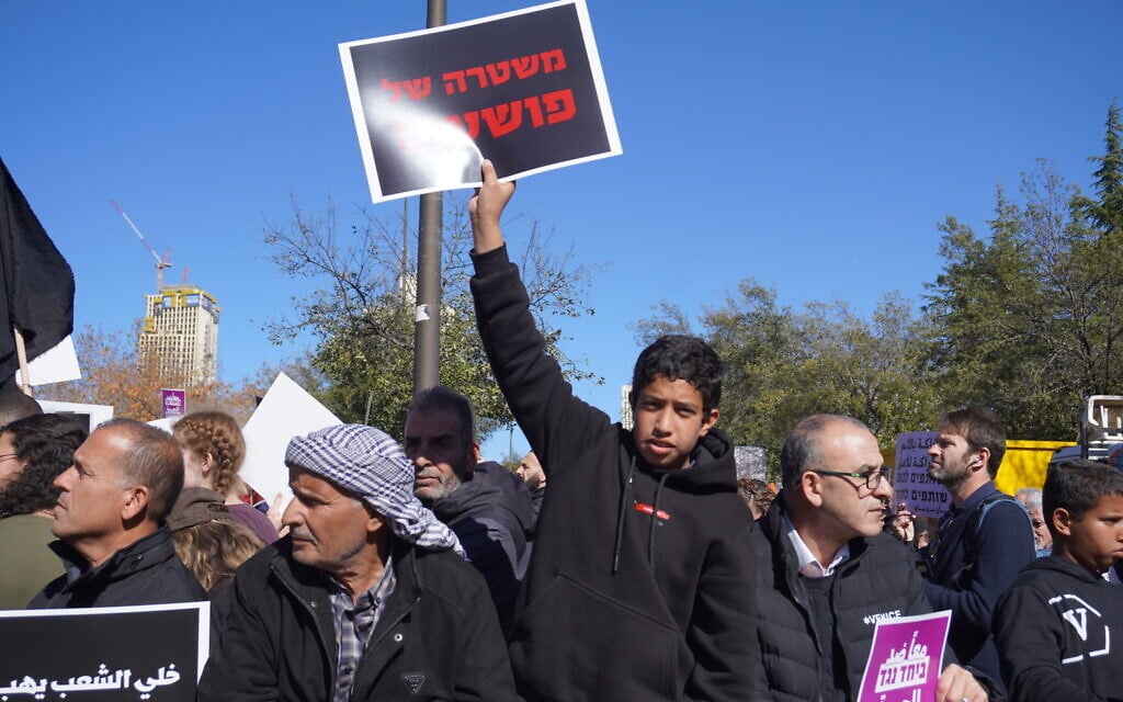 A young protester holds up a sign that reads: 'Police force of criminals' during a demonstration against how police have handled crime in Arab society, outside the Prime Minister's Office in Jerusalem, January 11, 2026. (Times of Israel)