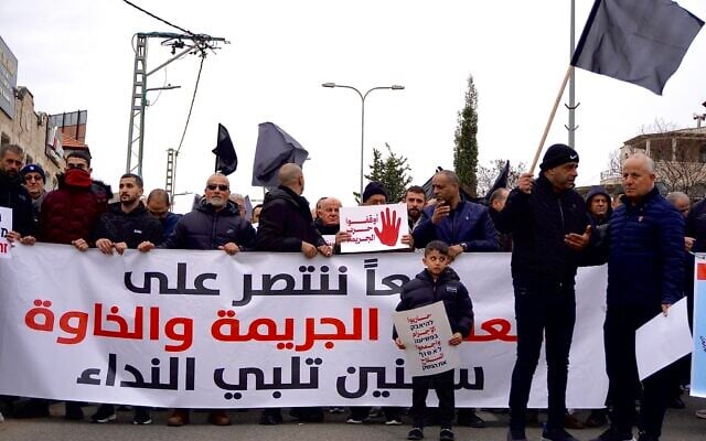 A child stands in front of a large banner that reads, ‘Together we will overcome violence, crime and extortion. Sakhnin answers the call,’ during a protest against the violent crime wave sweeping Arab society in Sakhnin, northern Israel on January 22, 2026. (Charlie Summers/Times of Israel)