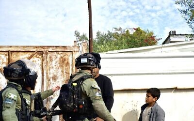 Officers in the Border Police's National Guard force approach a man on the street in Tarabin al-Sana on December 31, 2025. (Charlie Summers/Times of Israel)