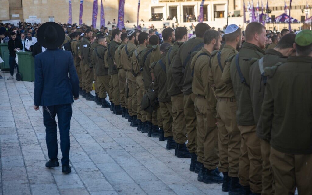An ultra-Orthodox man walks near IDF soldiers at the Western Wall plaza in the Old City of Jerusalem, January 5, 2026. (Chaim Goldberg/Flash90)