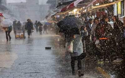 People walk in the rain at the Mahane Yehuda Market in Jerusalem, January 9, 2026 (Chaim Goldberg/Flash90)