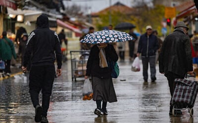 Shoppers walk in the rain at the Mahane Yehuda Market in Jerusalem, January 18, 2026. (Yonatan Sindel/Flash90)