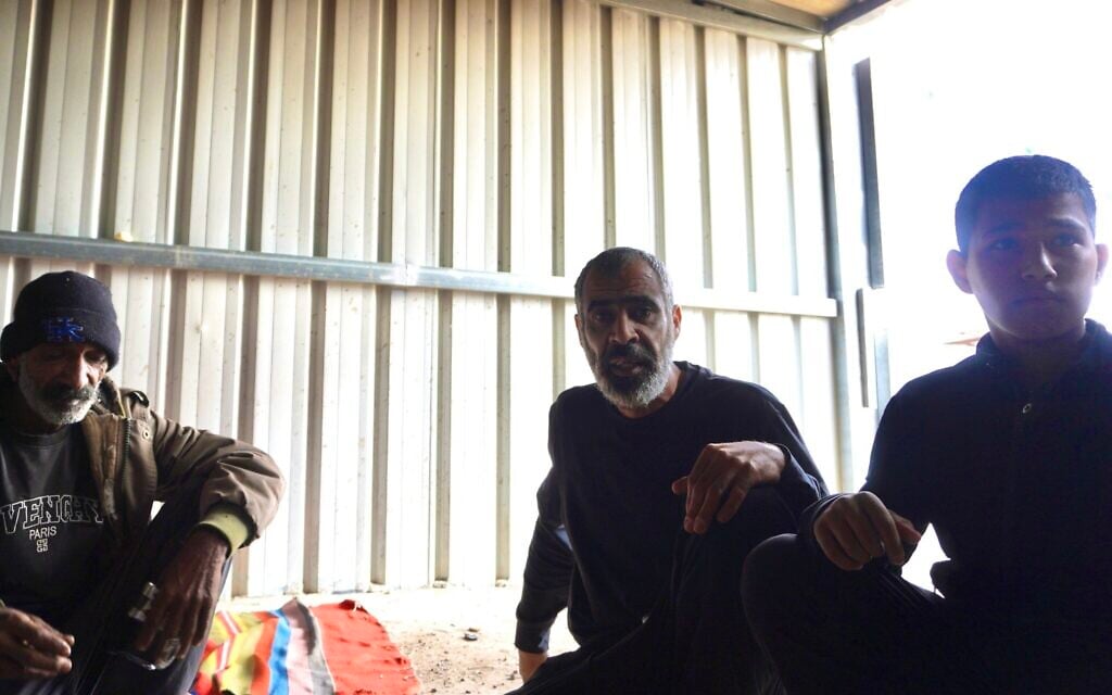 Nasser (left) and Ahmad (center) Tarabin, along with Ahmad's son, Adam, sit for tea in the southern village of Tarabin al-Sana on December 31, 2025. (Charlie Summers/Times of Israel)