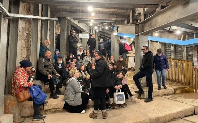Interior view of the ancient Pilgrims Road tunnel beneath Jerusalem showing original Herodian stone steps illuminated by modern lighting