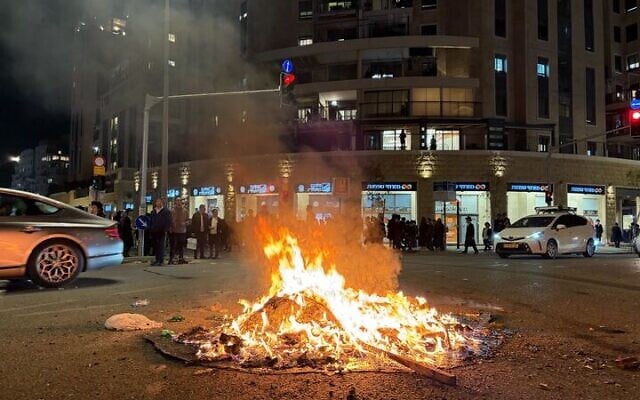 Haredim protesting against military conscription light a bonfire on a street in Jerusalem, January 6, 2026. (Sam Sokol/Times of Israel)
