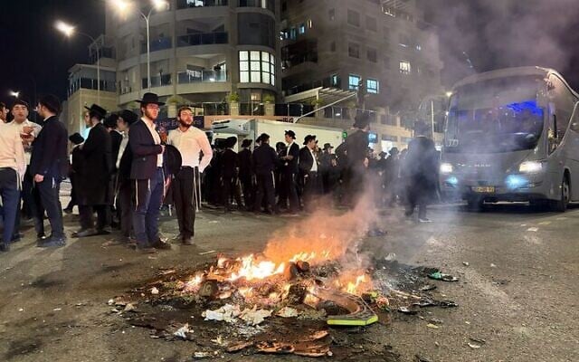 Haredim protesting against military conscription stand by a bonfire on a street in Jerusalem, January 6, 2026. (Sam Sokol/Times of Israel)
