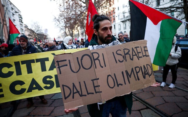 A man holds a placard reading "Israel out of the Olympics" during a protest against the environmental, economic, and social impact of the Milano-Cortina 2026 Winter Olympics in Milan, Italy, on February 7, 2026. (REUTERS/Guglielmo Mangiapane)