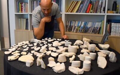 Eitan Klein, Deputy Director of the Israel Antiquities Authority Theft Prevention Unit, with dozens of stone vessel fragments found in a roughly 2000-year-old production site on the eastern slope of Mt. Scopus in Jerusalem, in a discovery announced on February 16, 2026. (Yoli Schwartz/Israel Antiquities Authority)