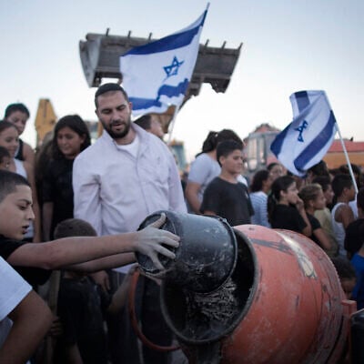 A Jewish boy throws water mixed with cement powder into a mixer in the Jewish Settlement of Adam, several kilometers from the West Bank city of Ramallah, as the Jewish residents symbolically resumed construction work on their settlement on September 1, 2010, in a defying move to protest the killing of four settlers by Palestinians near the West Bank town of Hebron the previous night. (MARCO LONGARI / AFP)