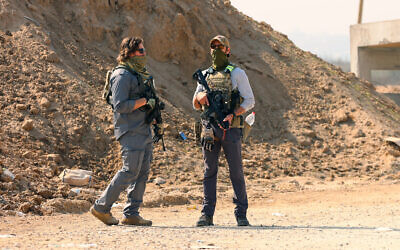 Illustrative: Armed men stand guard at a checkpoint manned by US and Egyptian security at the Netzarim corridor as displaced Palestinians make their way from the south to the northern parts of the Gaza Strip, on Salah al-Din road in central Gaza, on January 29, 2025. (Omar al-Qattaa/AFP)