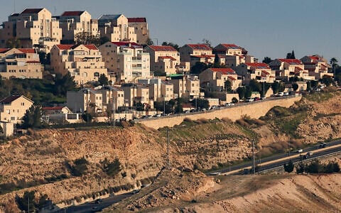 This picture taken from the 'E1 corridor' northeast of Jerusalem in the West Bank shows vehicles moving along a highway near the Israeli settlement of Maale Adumim (top) on February 4, 2026. (AHMAD GHARABLI / AFP)