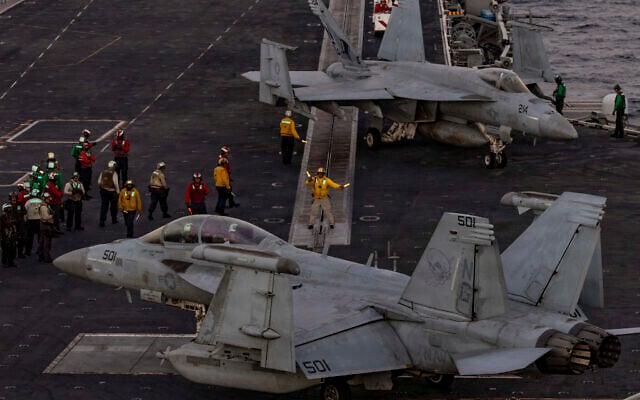 US Navy sailors directing an EA-18G Growler on the flight deck of the USS Abraham Lincoln.