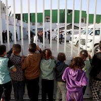 Palestinian children watch as patients prepare to leave the Gaza Strip for treatment through the Rafah border crossing between the Gaza Strip and Egypt after it was opened by Israel for a limited number of people, in Khan Younis in the southern Gaza Strip, on February 8, 2026. (Bashar Taleb/ AFP)