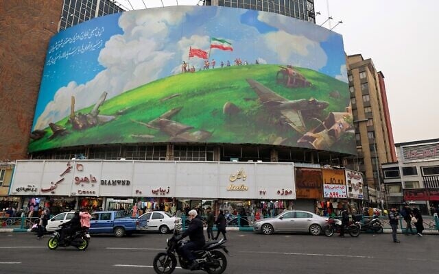 An Iranian rides a moped past a huge billboard depicting crashed Israeli and US aircraft, displayed on a building in Tehran's Valiasr Square on February 8, 2026. (ATTA KENARE / AFP) An Iranian rides a moped past a huge billboard depicting crashed Israeli and US aircraft, displayed on a building in Tehran's Valiasr Square on February 8, 2026. (ATTA KENARE / AFP)