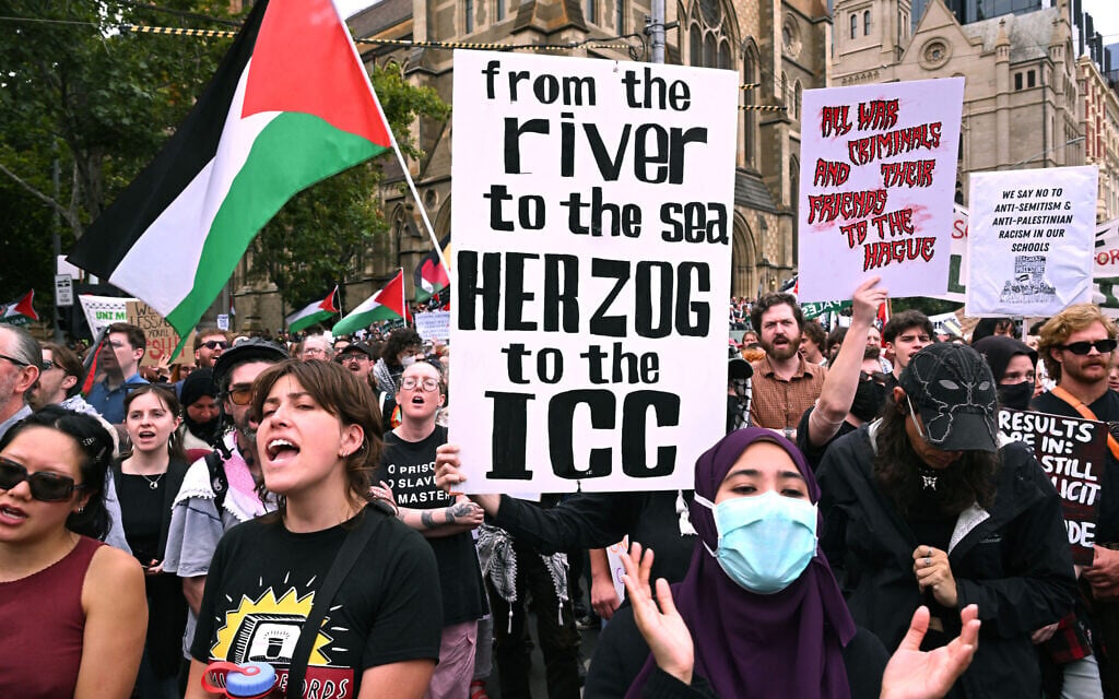 People hold up placards during a protest rally against a four-day state visit by President Isaac Herzog, in Melbourne on February 9, 2026. (William WEST / AFP)