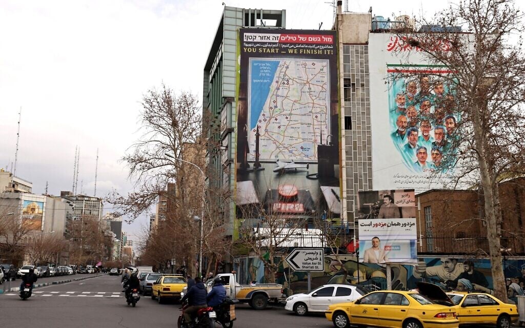A giant billboard displaying a map of potential targets in Tel Aviv along with a warning message reading, 'You start, we finish!' is seen at Palestine Square as traffic move through the area, in Tehran on February 9, 2026. (ATTA KENARE / AFP)