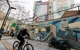 A man cycles past a mural and a giant billboard displaying a map of potential targets in the Tel Aviv area along with a warning message reading, 'You start, we finish!' in Palestine Square, in Tehran, Iran, on February 9, 2026. (ATTA KENARE / AFP)