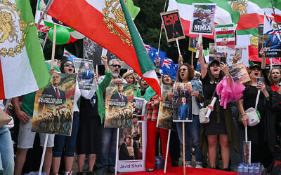 Members of the Iranian community wave flags as they march during a rally in Sydney on February 14, 2026, calling for stronger international action and urging the United States to intervene against the current Iranian regime. (Photo by Saeed KHAN / AFP)