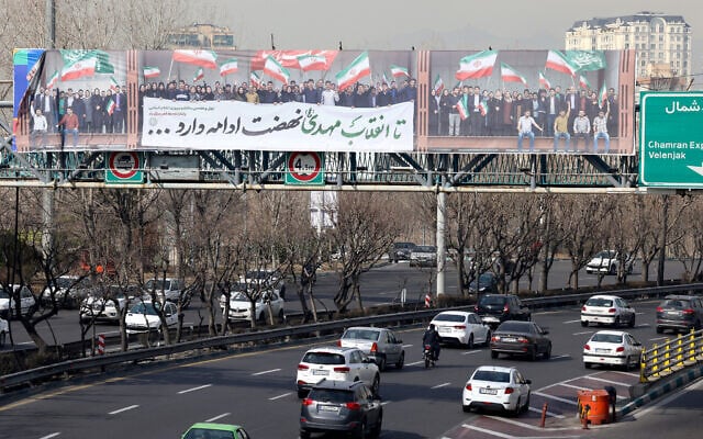 Vehicles drive along a highway under a pedestrian bridge with a huge banner showing people waving the Iranian flag, in Tehran, Iran, on February 18, 2026. (ATTA KENARE / AFP) Vehicles drive along a highway under a pedestrian bridge with a huge banner showing people waving the Iranian flag, in Tehran, Iran, on February 18, 2026. (ATTA KENARE / AFP)