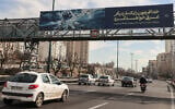 Vehicles drive along a highway under a banner with Supreme Leader Ali Khamenei's threat against US warships,  in Tehran on February 18, 2026. (ATTA KENARE / AFP)