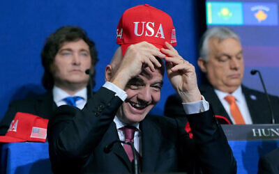 FIFA President Gianni Infantino holds up a USA hat as he attends the inaugural meeting of the Board of Peace at the Institute of Peace on February 19, 2026 in Washington. (Chip Somodevilla/Getty Images/AFP)