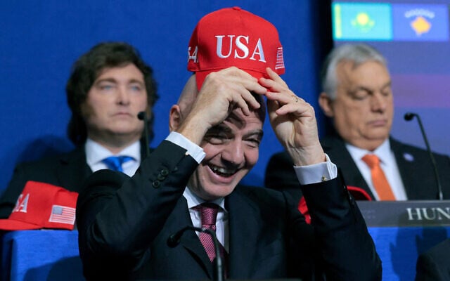 FIFA President Gianni Infantino holds up a USA hat as he attends the inaugural meeting of the Board of Peace at the Institute of Peace on February 19, 2026 in Washington. (Chip Somodevilla/Getty Images/AFP) FIFA President Gianni Infantino holds up a USA hat as he attends the inaugural meeting of the Board of Peace at the Institute of Peace on February 19, 2026 in Washington. (Chip Somodevilla/Getty Images/AFP)