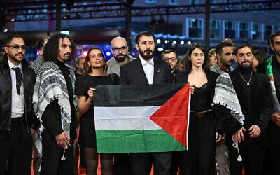 The team of the film "Chronicles from the Siege" hold a Palestinian flag as they arrive on the red carpet for the Award Ceremony of the 76th Berlinale, Europe's first major film festival of the year, in Berlin on February 21, 2026. (RALF HIRSCHBERGER / AFP)