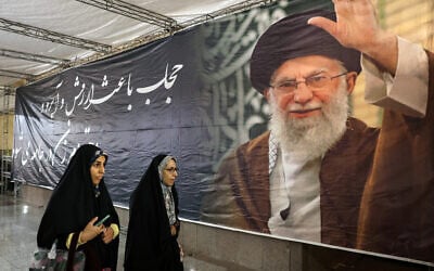 Iranian women walk past a banner bearing a portrait of Iran's supreme leader Ayatollah Ali Khamenei during the Iranian-Islamic fashion design fair at the Imam Khomeini Grand Mosque in Tehran on February 22, 2026. (AFP)