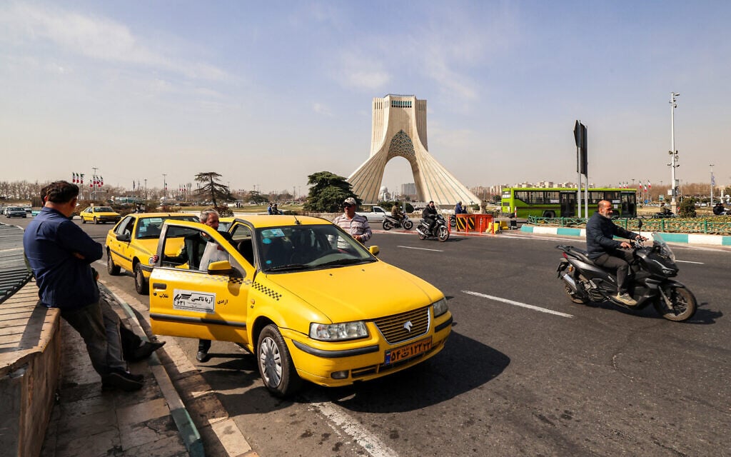 A man enters a taxi cab at Azadi (Freedom) Square near the landmark Azadi Tower in Tehran on February 23, 2026 (ATTA KENARE / AFP)
