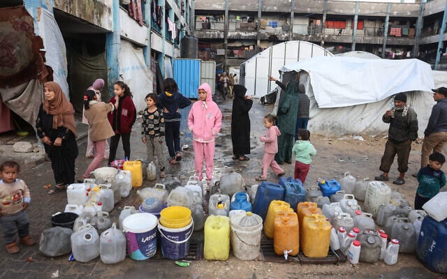 Children stand next to water containers at a makeshift camp sheltering displaced Palestinians in Khan Younis, in the southern Gaza Strip, on February 24, 2026. (Bashar Taleb / AFP) Children stand next to water containers at a makeshift camp sheltering displaced Palestinians in Khan Younis, in the southern Gaza Strip, on February 24, 2026. (Bashar Taleb / AFP)