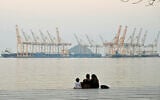 A family sits against the backdrop of a dockyard off the coastal city of Fujairah, in the Strait of Hormuz in the northern United Arab Emirates on February 25, 2026. (Giuseppe CACACE / AFP)