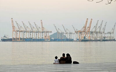 A family sits against the backdrop of a dockyard off the coastal city of Fujairah, in the Strait of Hormuz in the northern United Arab Emirates on February 25, 2026. (Giuseppe CACACE / AFP)