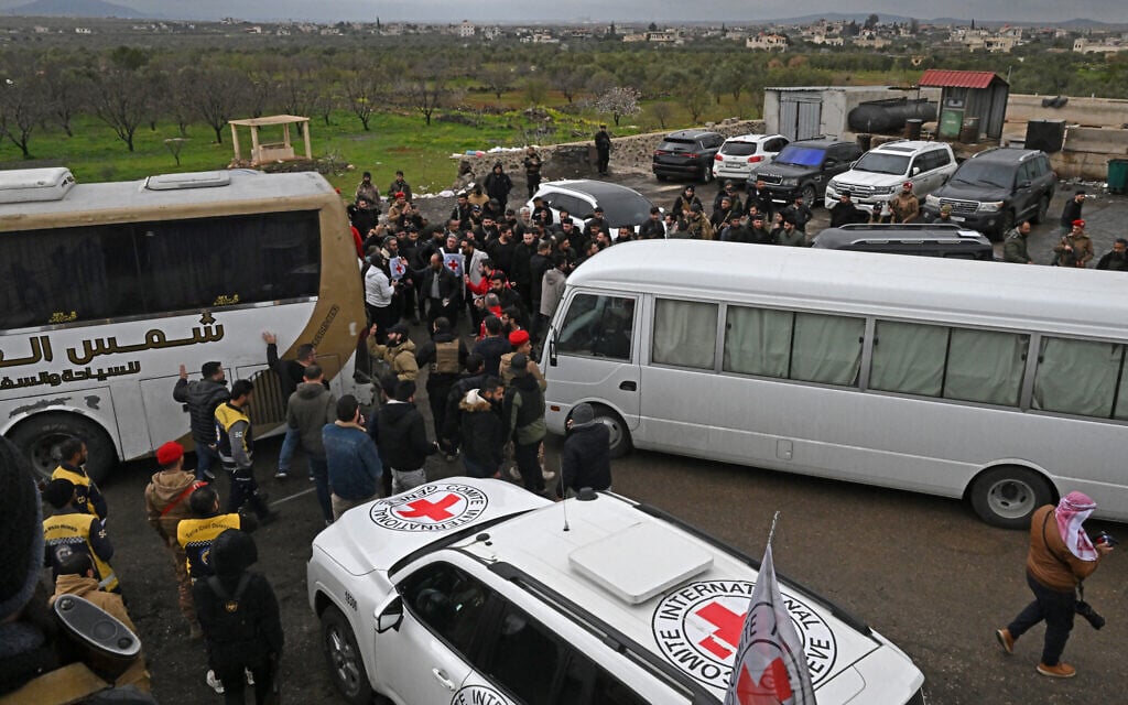Security personnel and officials gather next to buses with prisoners on board during an exchange of prisoners' ceremony between Syrian authorities and Druze fighters, in Sweida, Syria, on February 26, 2026. (LOUAI BESHARA / AFP) Security personnel and officials gather next to buses with prisoners on board during an exchange of prisoners' ceremony between Syrian authorities and Druze fighters, in Sweida, Syria, on February 26, 2026. (LOUAI BESHARA / AFP)